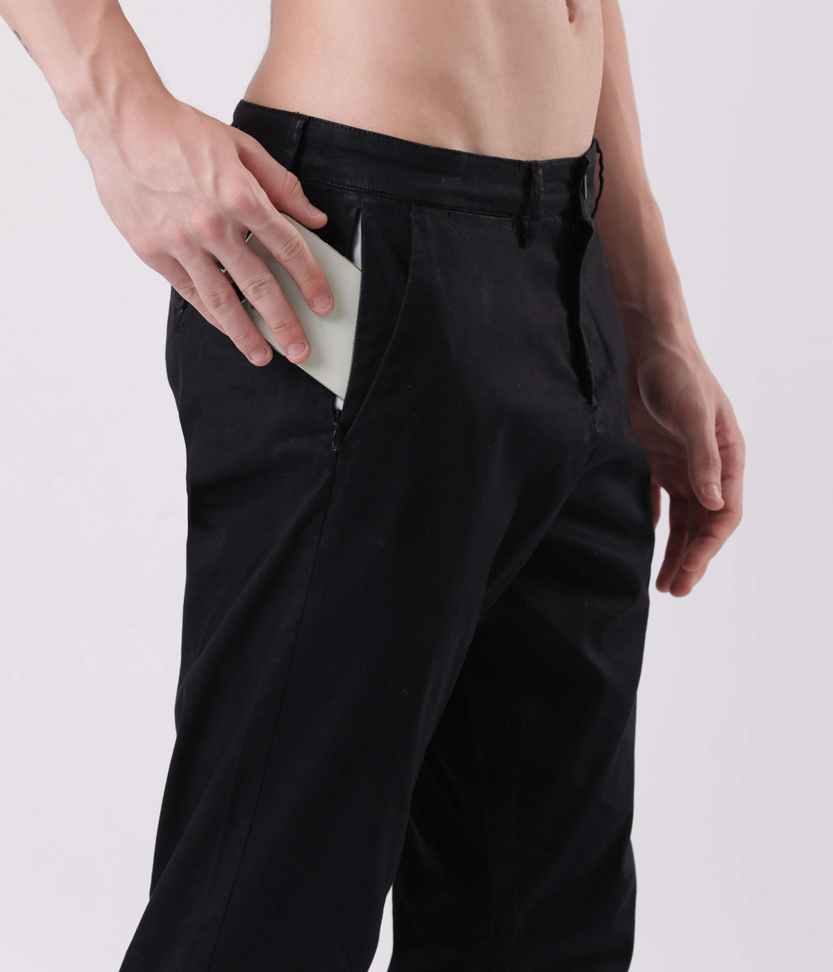 Man wearing Turms Black Sea Chino, placing a phone in the side pocket for convenient storage.