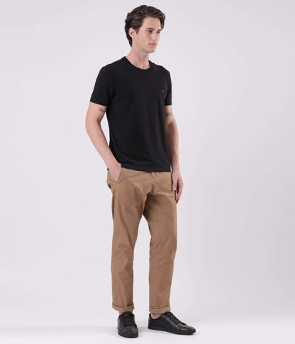 A model wearing Turms Dessert Mirage outfit featuring a black t-shirt and beige chinos for everyday luxury.