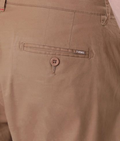 Close-up of a Turms Chino's back pocket showcasing button detail and brand label, highlighting style and quality.