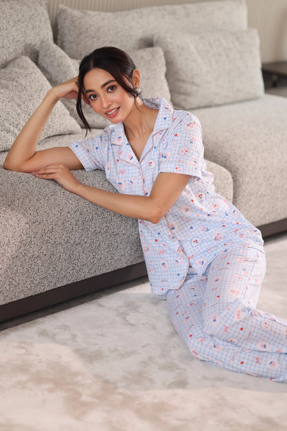 Woman in a patterned dress sitting on a gray sofa in a living room.