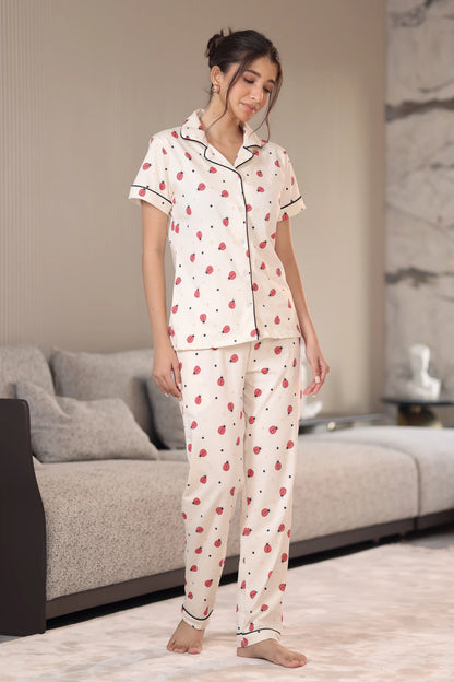 Woman wearing a cream-colored pajama set with red patterns in a living room.