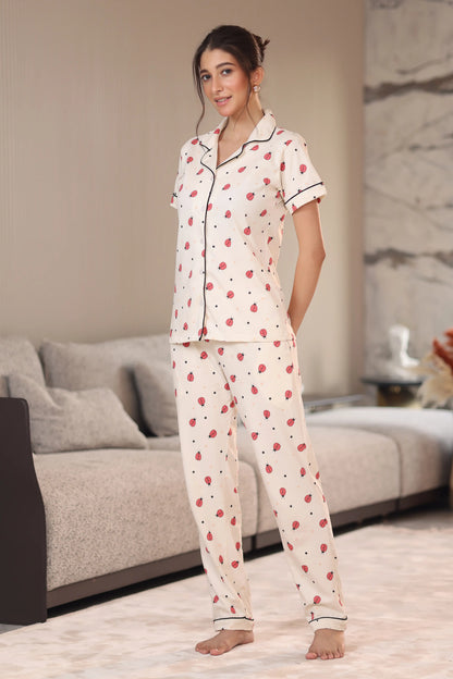 Woman wearing a white pajama set with red patterns in a living room.