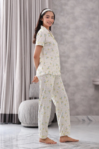 Woman wearing a Bunny print pajama set in a room with gray curtains and a marble floor.