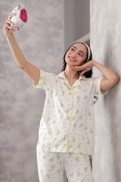 Woman in a printed pajama set holding a pink object against a gray background