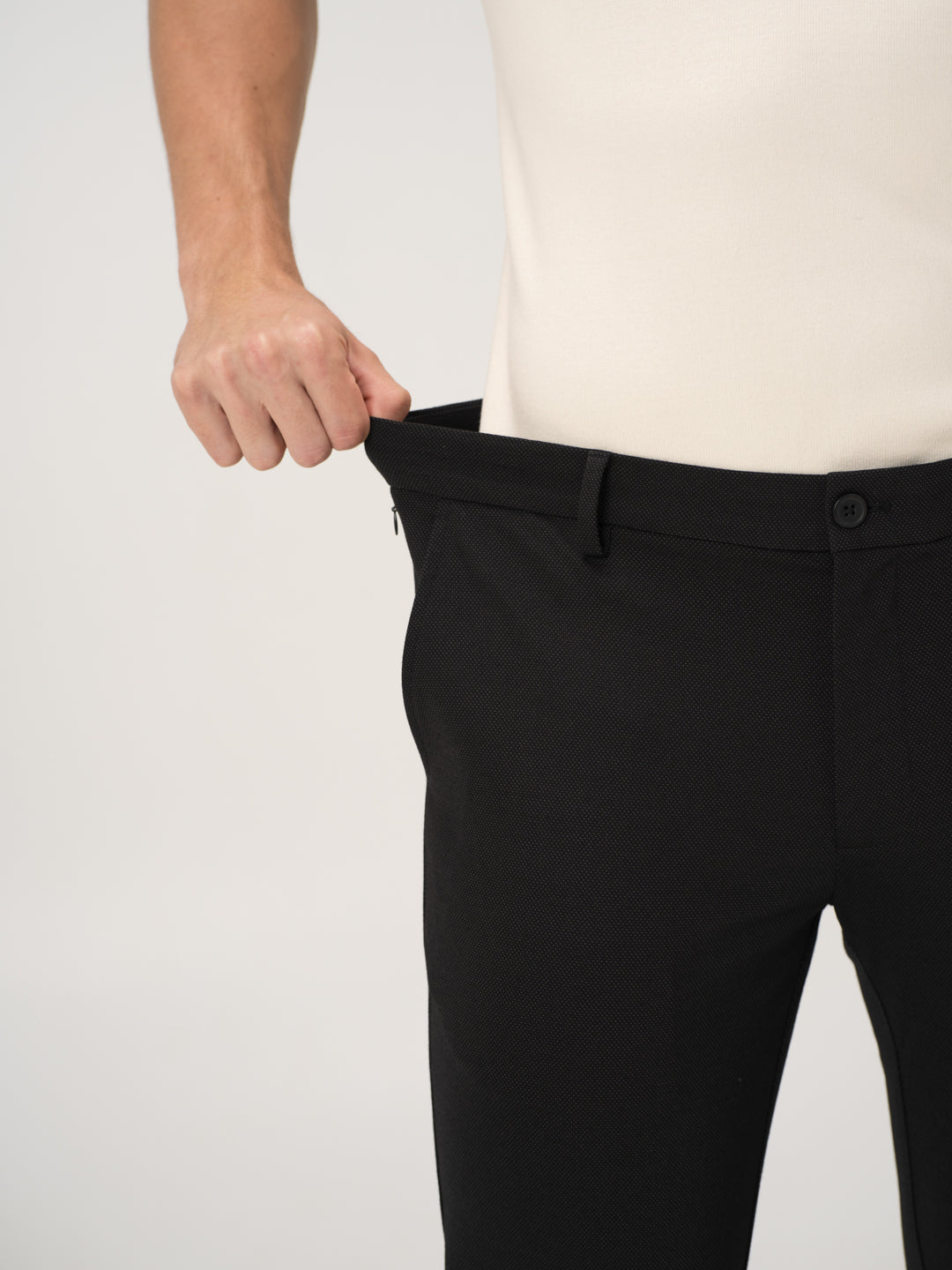 Close-up view of black stretchable trousers by pant project, focusing on the waistband being stretched