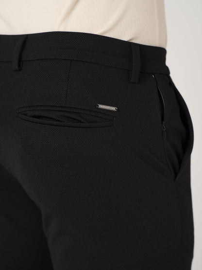 Close-up view of black stretchable trousers by pant project, focusing on the back pocket detail