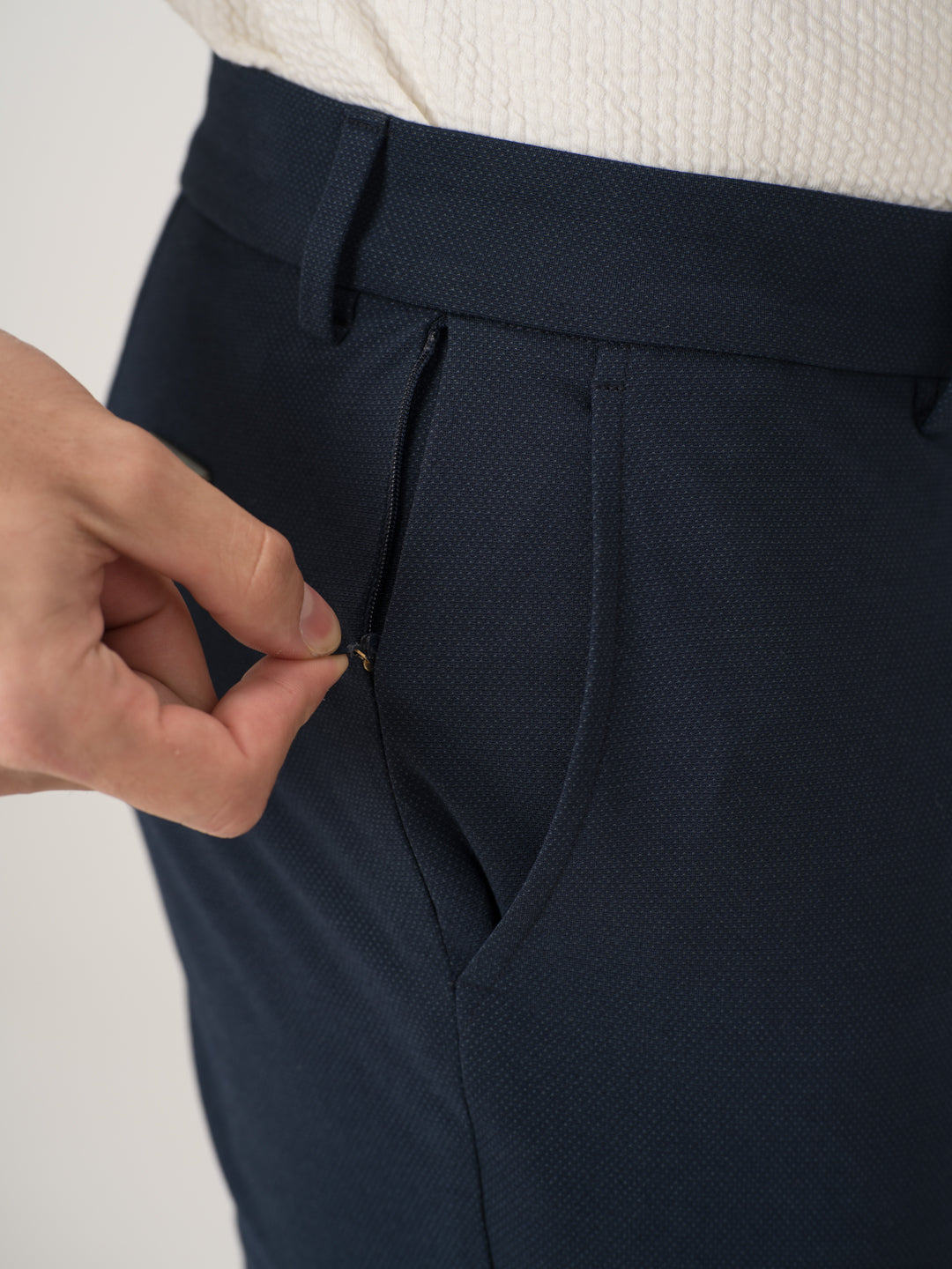 Close-up view of navy blue stretchable trousers by pant project, focusing on the zippered pocket detail
